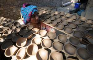 a potter carry earthen lamps to dry at a workshop ahead of the Diwali festival near Bus Stand in Jammu on Friday.Tribune Photo:Inderjeet Singh